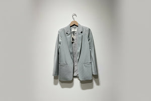 Light gray blazer on a hanger against a plain background