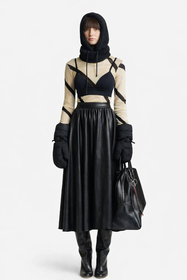 Person wearing a black and beige outfit with a leather skirt on a white background